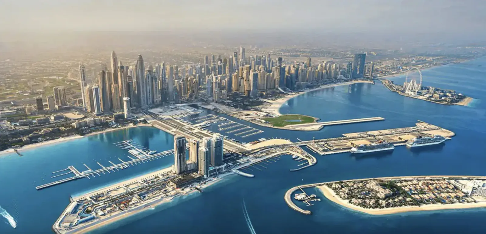 Aerial view of Dubai Marina's skyline, superyacht marina, and turquoise waters at sunset.