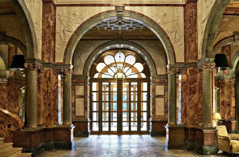 Grand entrance hall of Kimpton Fitzroy London with ornate arches, columns, and large arched doors.