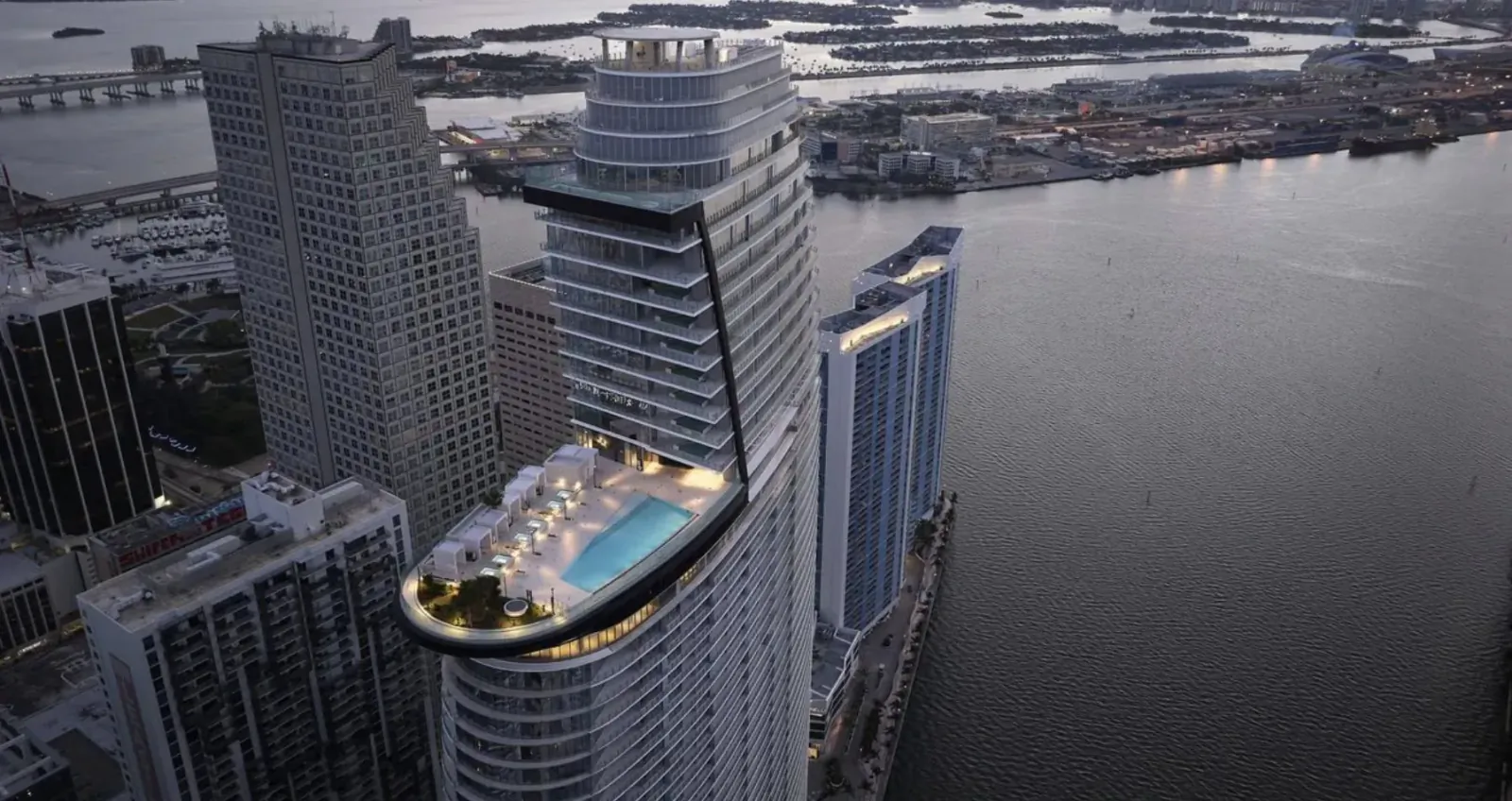 Aerial view of Aston Martin Residences Miami: sleek high-rise with rooftop infinity pool overlooking city skyline and bay