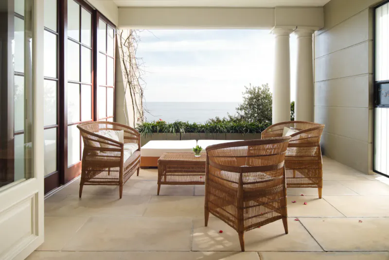 Elegant rattan outdoor lounge on terrace at 21 Nettleton Boutique Hotel, Cape Town, with ocean and mountain view.