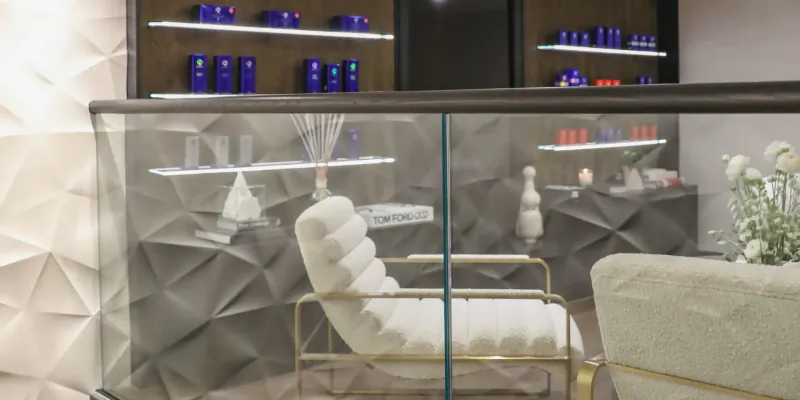 Elegant Mallucci London aesthetics clinic interior with white plush chair, blue product shelves, and geometric decor.