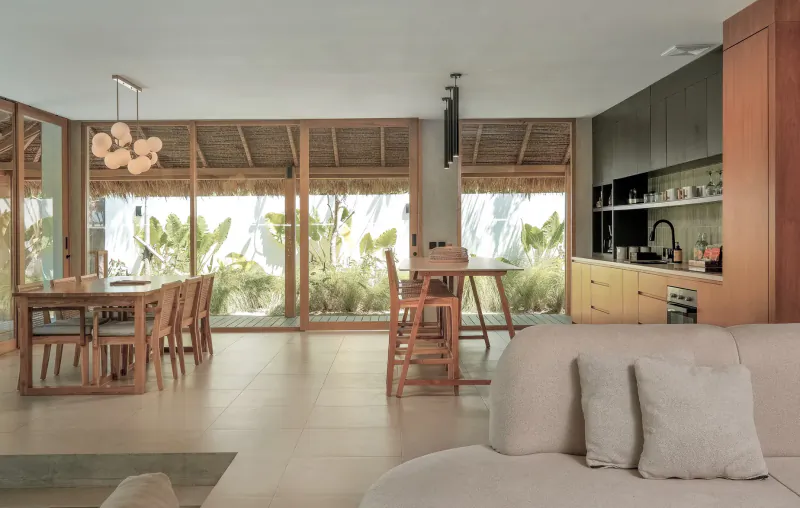 Spacious modern kitchen and dining area in beachfront villa with wooden accents, tropical plants, and large windows