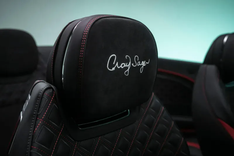 Bentley car seats with embroidered 'Choi Say' signature on black suede headrests and red stitching
