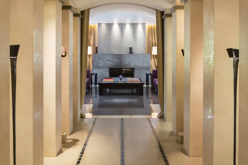 Elegant arched gallery hallway at Terre Blanche with beige columns, black coffee table, and modern fireplace.
