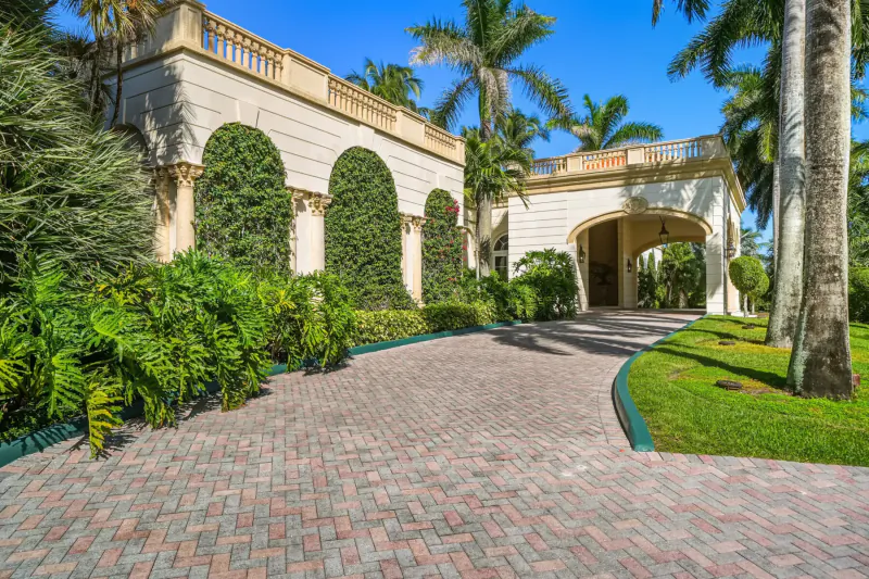 Edgewater Drive Villa in Sans Souci: beige arched entrance with palm trees, lush greenery, and brick driveway