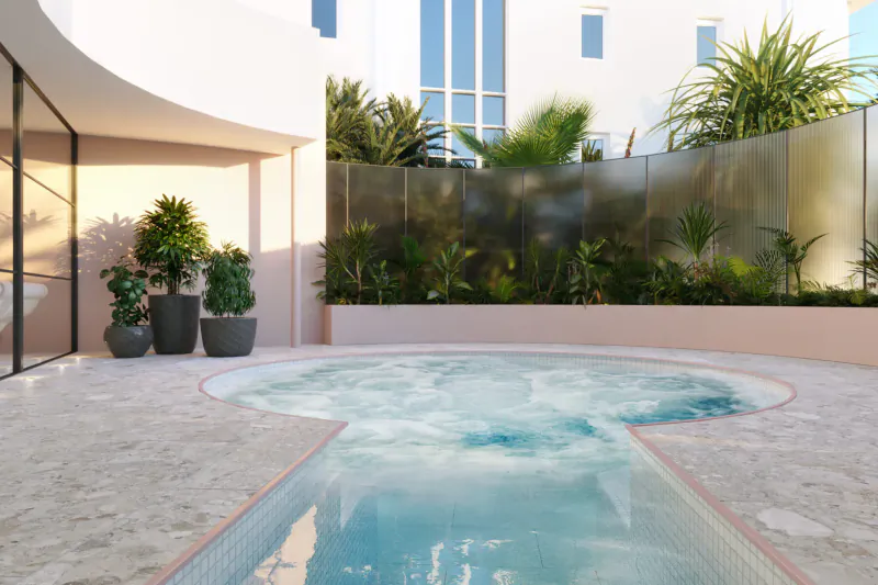 Luxury outdoor hot tub with bubbling turquoise water at St Moritz Hotel, surrounded by palms, plants, and modern pink architecture.