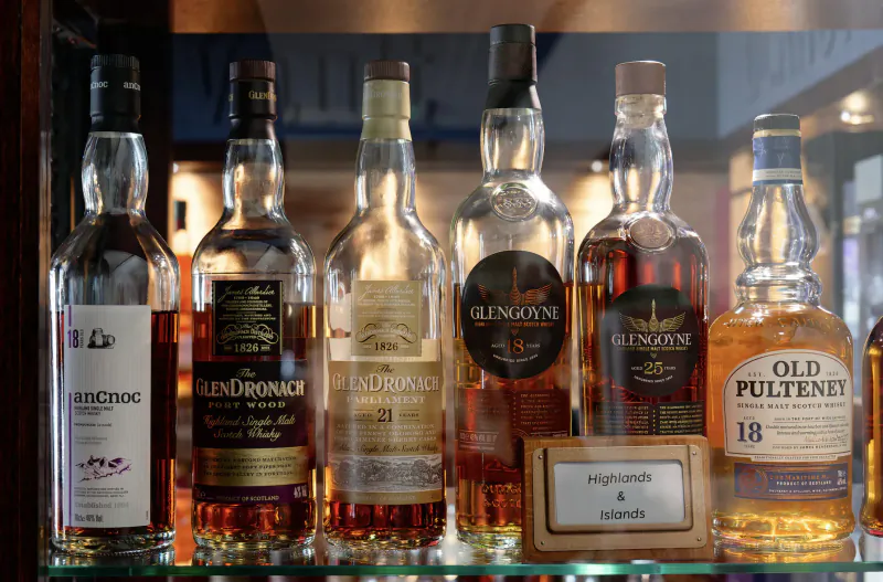 Glass cabinet displaying Glenrothes, GlenDronach, Glenfiddich, Glenlivet, and Old Pulteney whisky bottles with age labels.