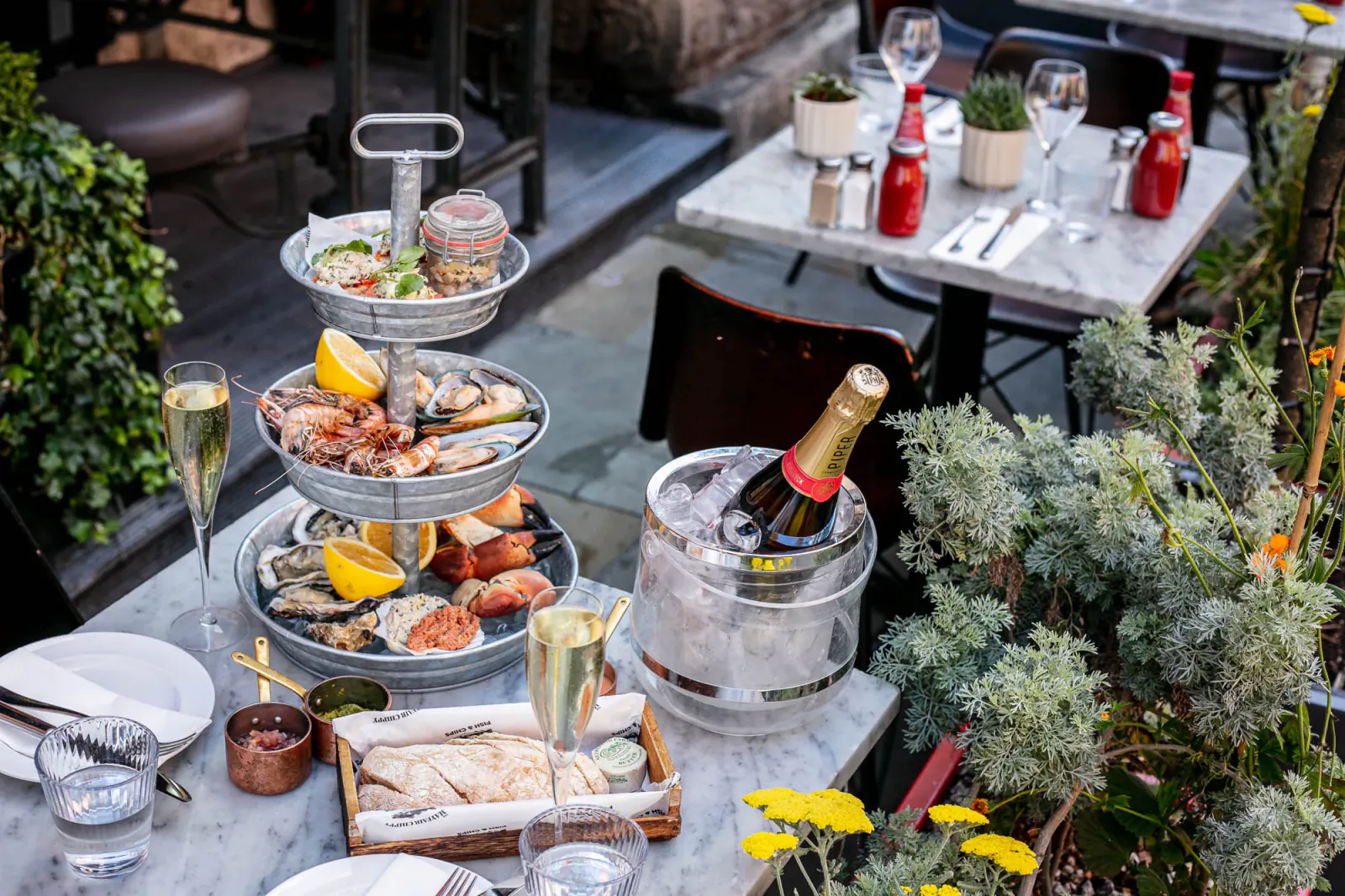 Tiered seafood platter with lobster, crab, oysters on outdoor table with champagne in ice bucket, glasses, at Lobster Pot Booth.