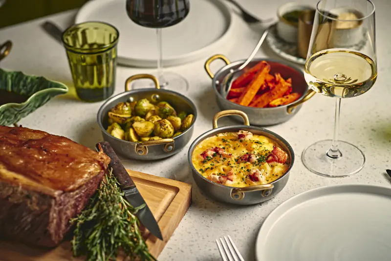 Elegant tablescape at Park Corner Brasserie: sliced roast beef, Brussels sprouts, carrots, eggs, wine glasses