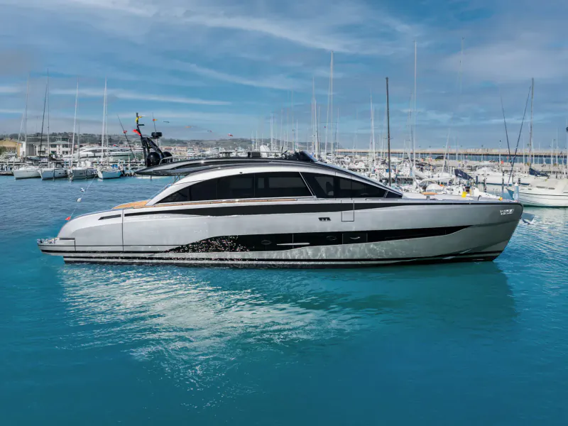 Sleek white Pershing GTX70 luxury yacht docked in marina with masts and blue water.