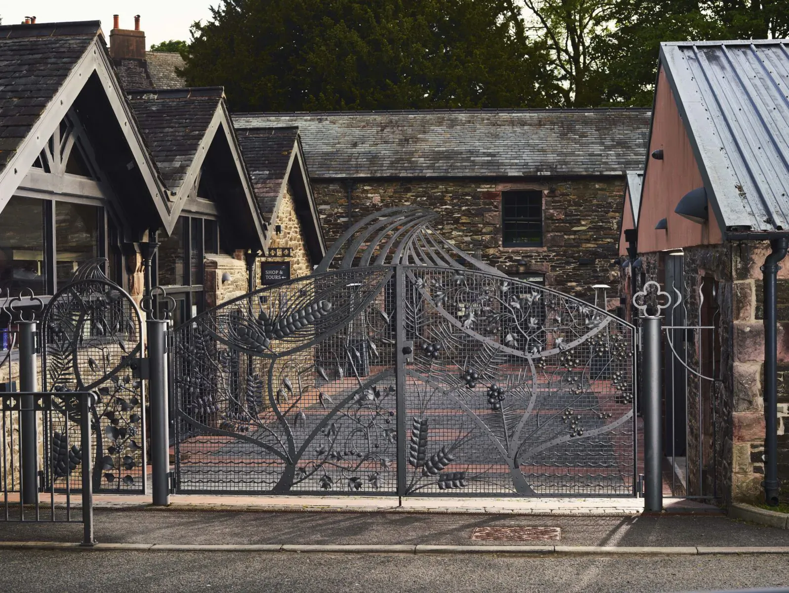 Ornate wrought iron double gates with floral and leaf designs at stone distillery courtyard entrance