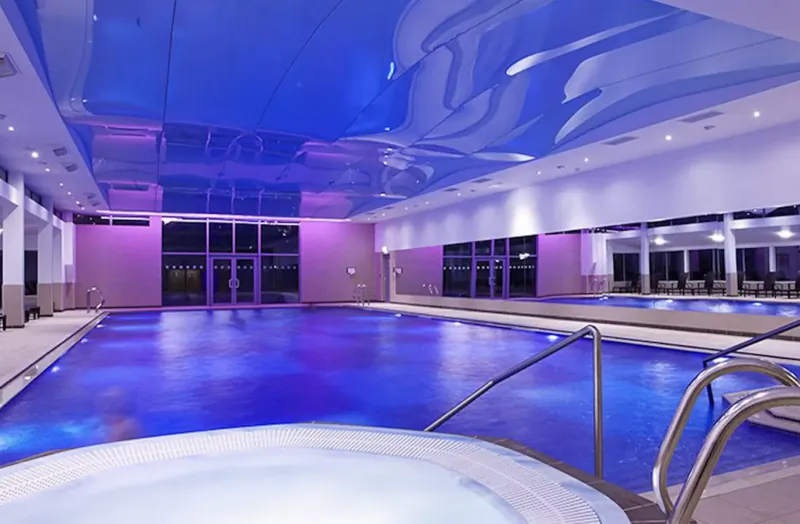 Tranquil indoor pool and hot tub at St. Brelade’s Bay Hotel, lit in glowing blue and purple tones.
