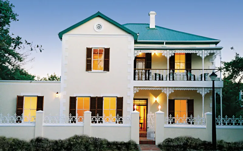 Evergreen Manor and Spa, a cream two-story Victorian house with green roof and lit windows at dusk in Stellenbosch.