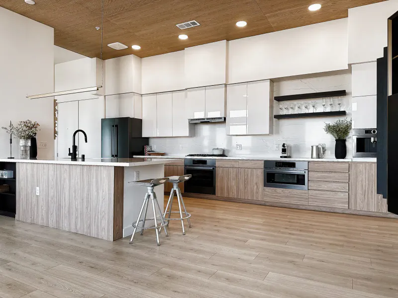 Modern kitchen in Ariva Serviced Residences with white cabinets, wood island, bar stools, and pendant lights