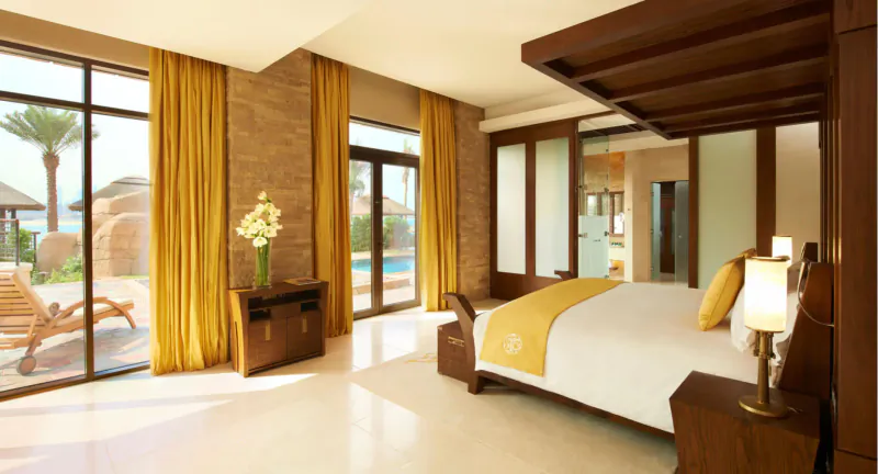 Luxurious Sofitel Dubai The Palm bedroom with king bed, yellow accents, pool view through glass doors.