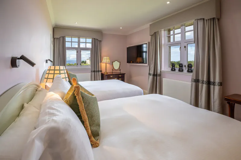 Luxury twin bedroom in Fairmont St Andrews Manor Home with garden views, plush beds, lamps, TV, and elegant decor.