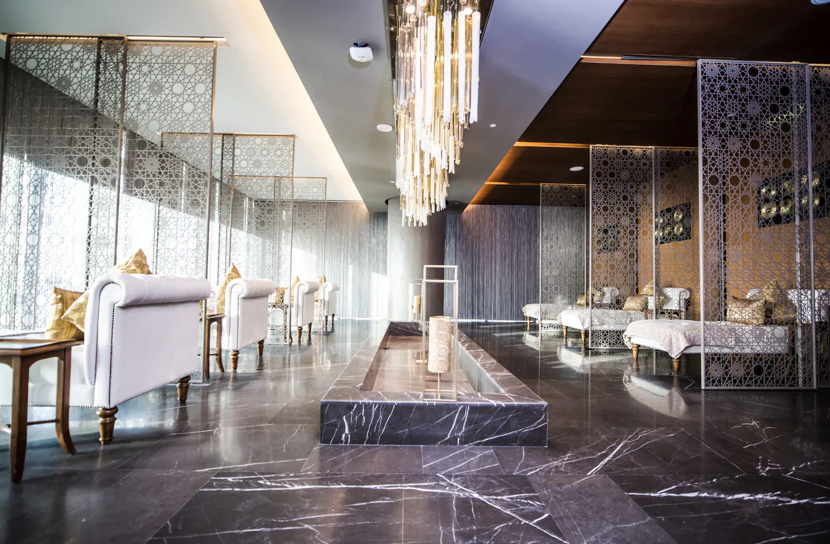 Elegant Naturelife Spa lounge at Rixos Premium JBR, Dubai: white sofas, daybeds, crystal chandeliers, marble floors, lattice screens.