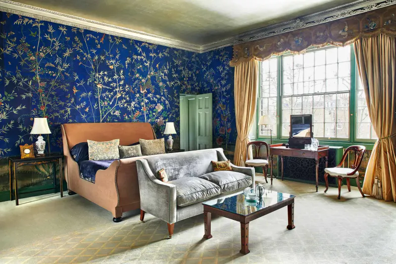Elegant lounge in Home House club with blue floral wallpaper, tan sofa, desk, and large window.