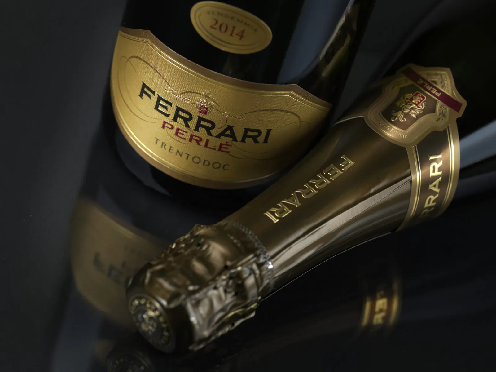 Ferrari Perlé Trento 2014 sparkling wine bottle from TrentoDOC, luxury gold label, angled view