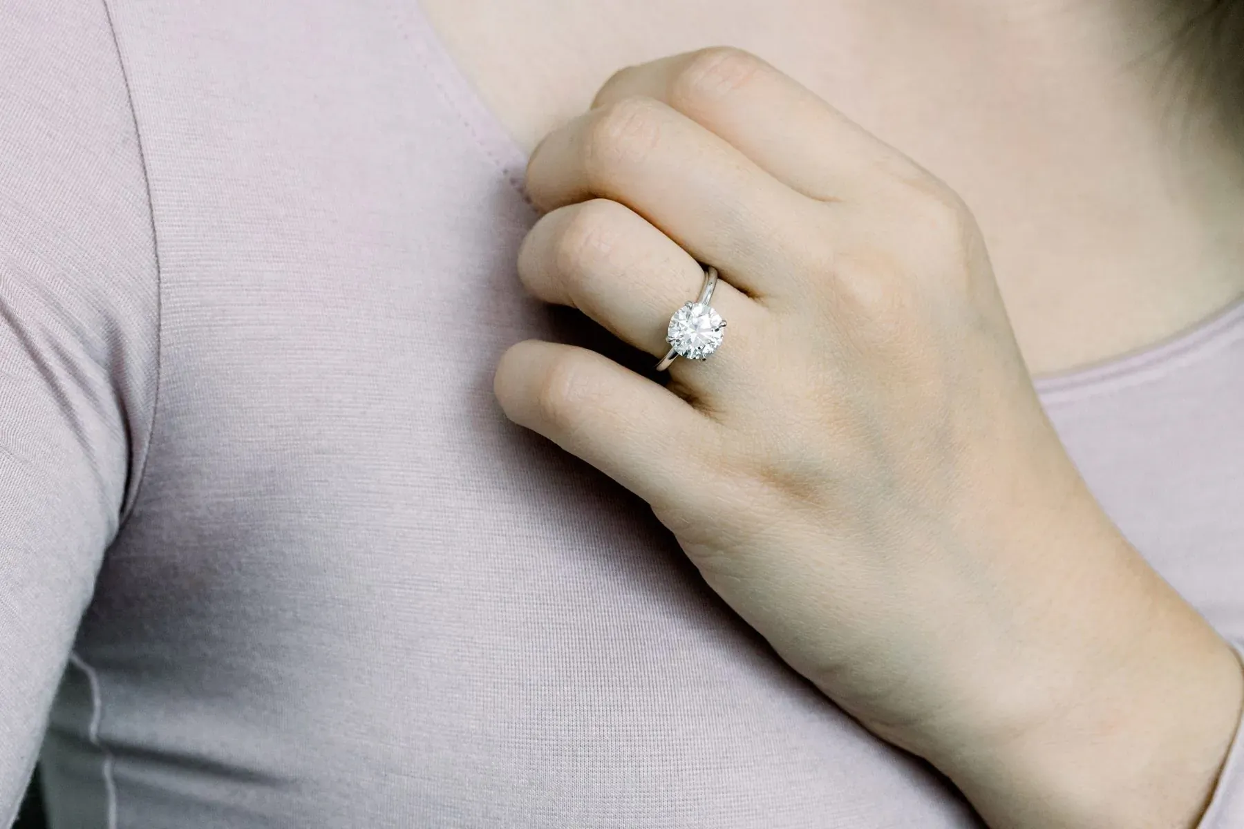 Close-up of woman's hand wearing a luxury round diamond engagement ring on her ring finger