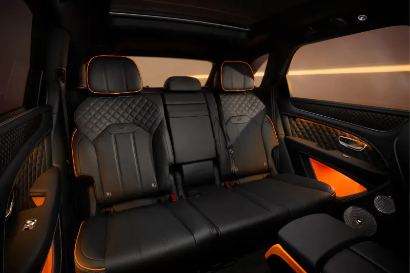 Bentley Bentayga Black Edition interior: black leather seats with orange accents and ambient lighting.