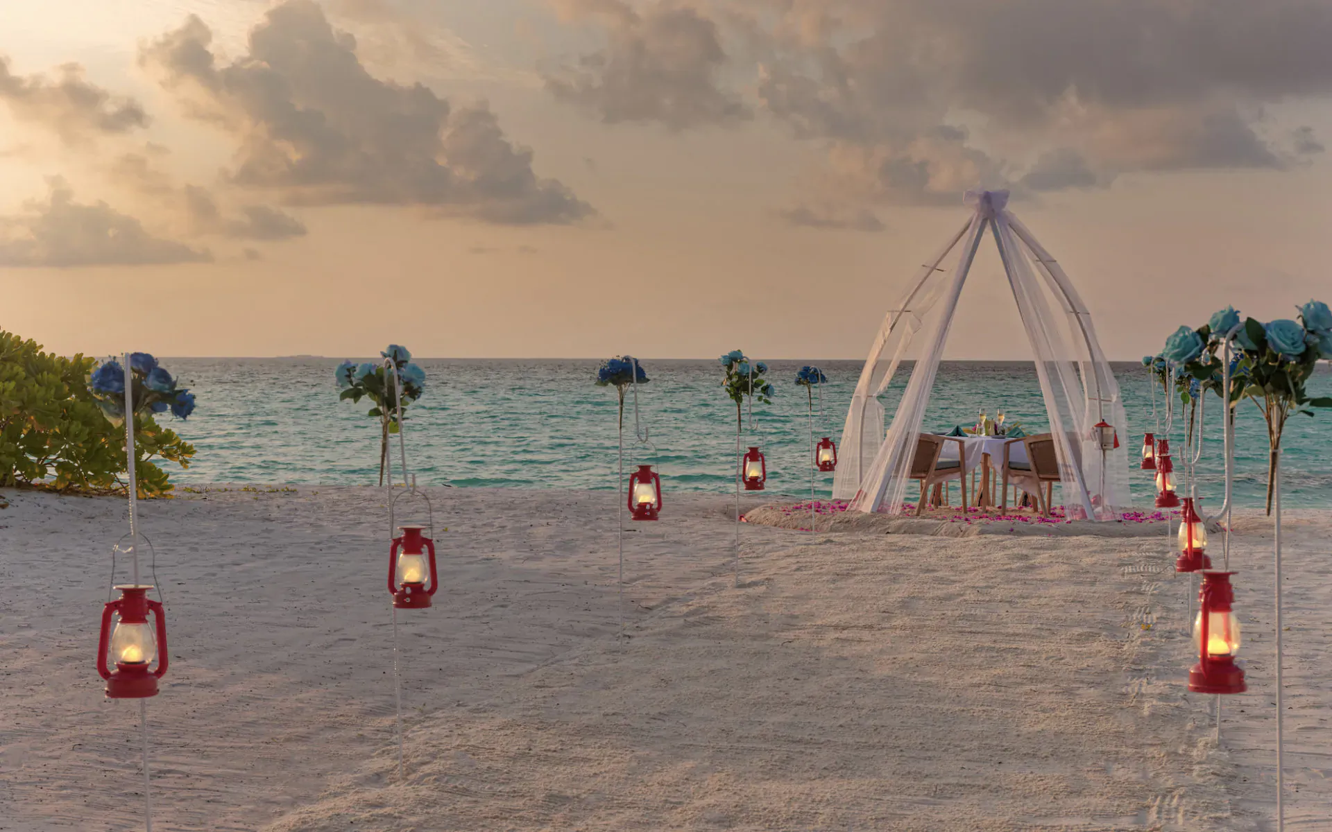 Romantic beach dinner for two under white-draped pavilion at sunset, lanterns on Maldives shore.
