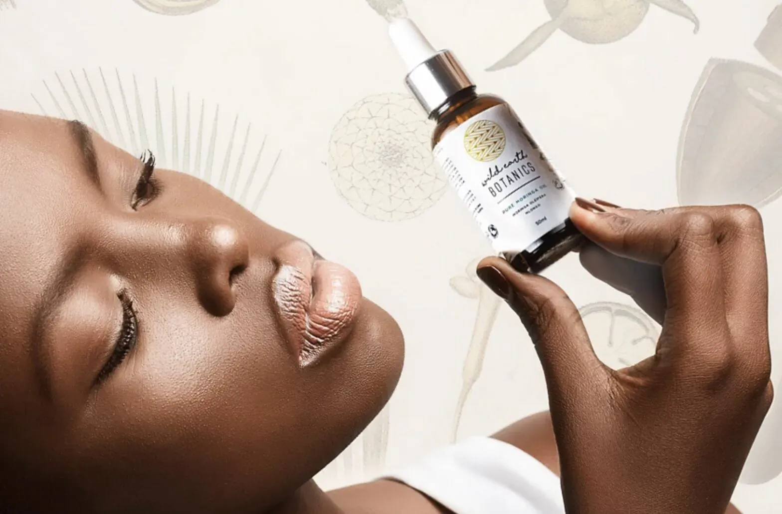 Close-up of Black woman holding Wild Earth Botanics skincare dropper bottle, pursing lips, with dandelion motifs