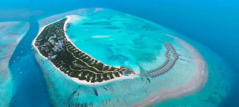Aerial view of Hideaway Beach Resort & Spa on crescent-shaped tropical island with turquoise lagoons and overwater villas