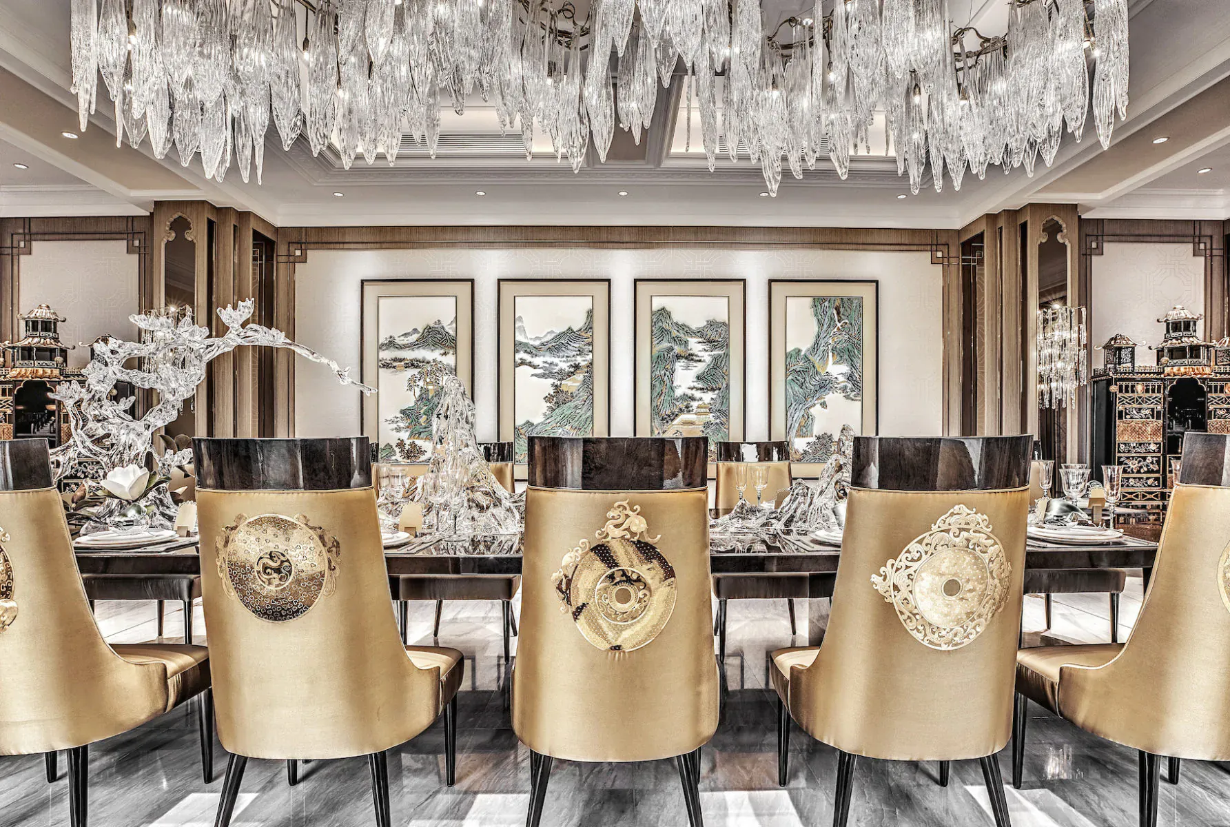 Luxurious dining room with gold Versace chairs at long table, crystal chandelier, ornate decor, and Chinese paintings.