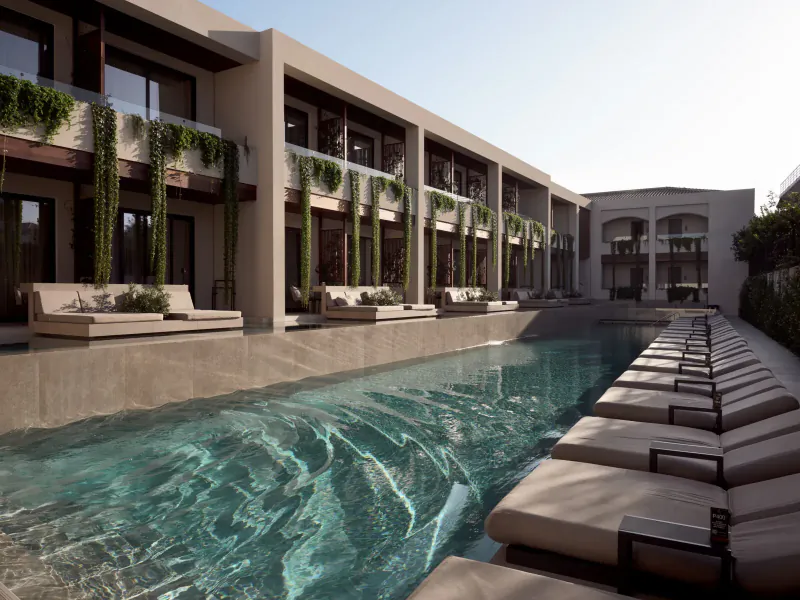 Luxury infinity pool at Contessina Hotel Zakynthos with lounge chairs, modern beige architecture, and greenery.