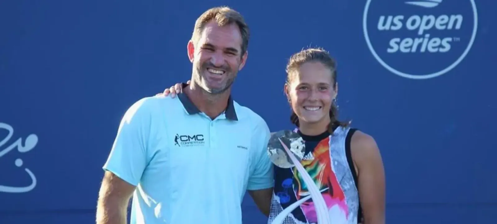 Carlos Martinez Comet smiles with young girl holding trophy at US Open Series, blue court backdrop