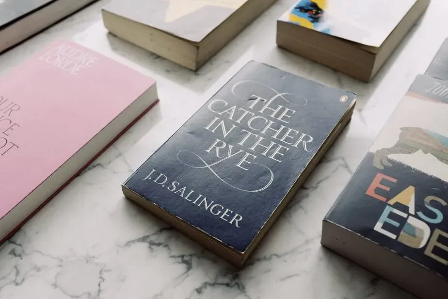 Close-up of books on marble surface: The Catcher in the Rye by J.D. Salinger, East of Eden, others with foil stamping, embossing, textures.