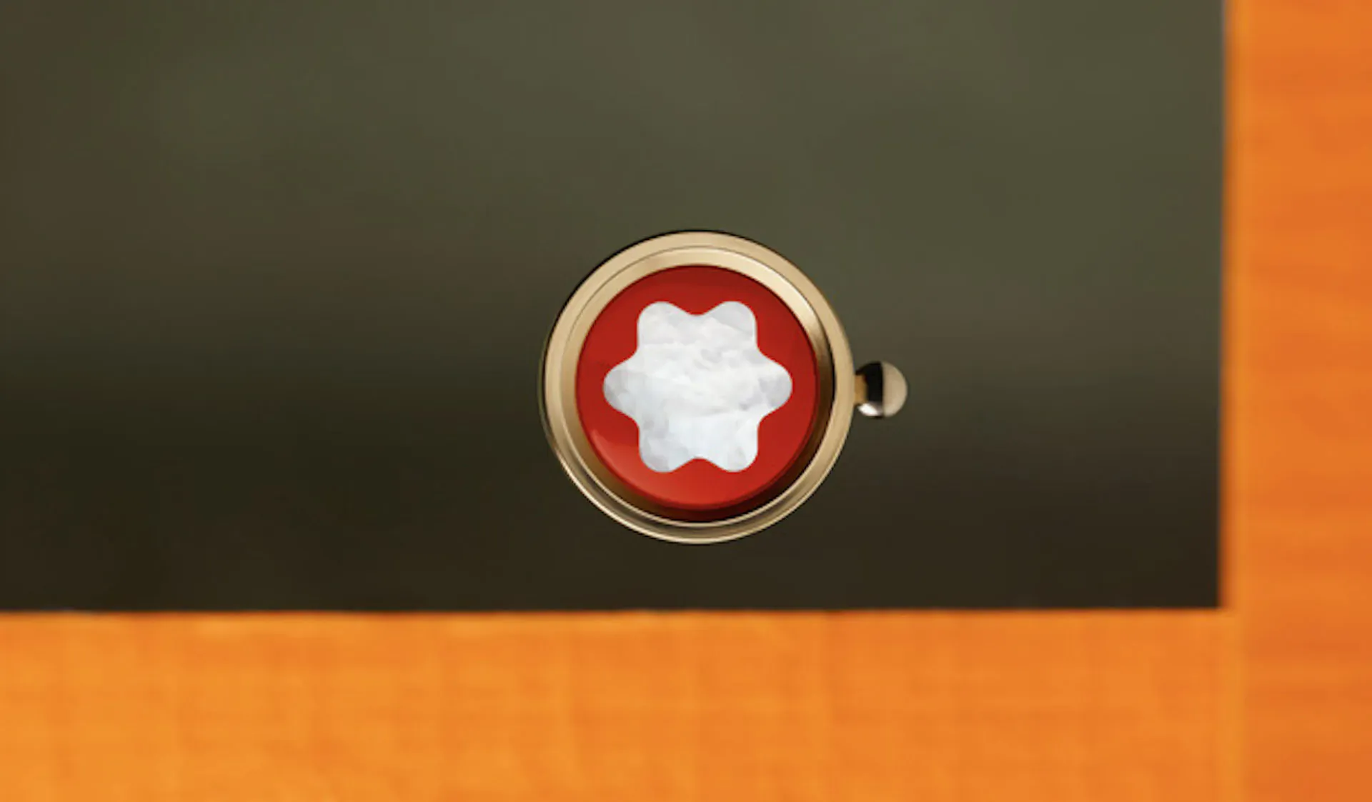 Close-up of Montblanc logo: white star emblem in red circular badge on green surface.