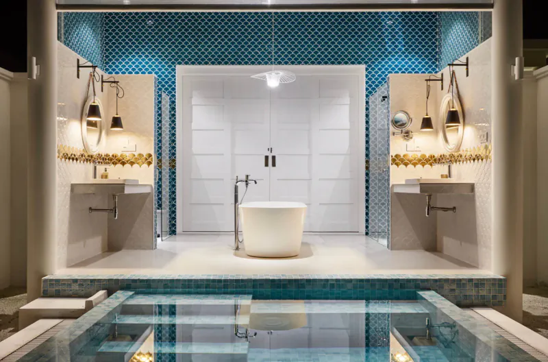 Luxurious spa bathroom with freestanding white bathtub, teal mosaic walls, gold fixtures, and reflecting pool.