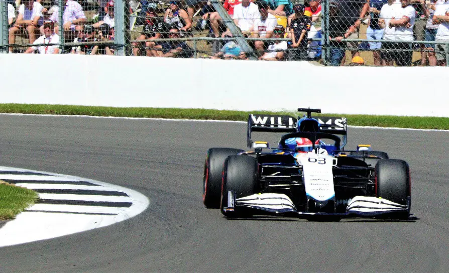 Williams FW46 Formula 1 car with FW46 livery speeds through Silverstone corner amid spectators
