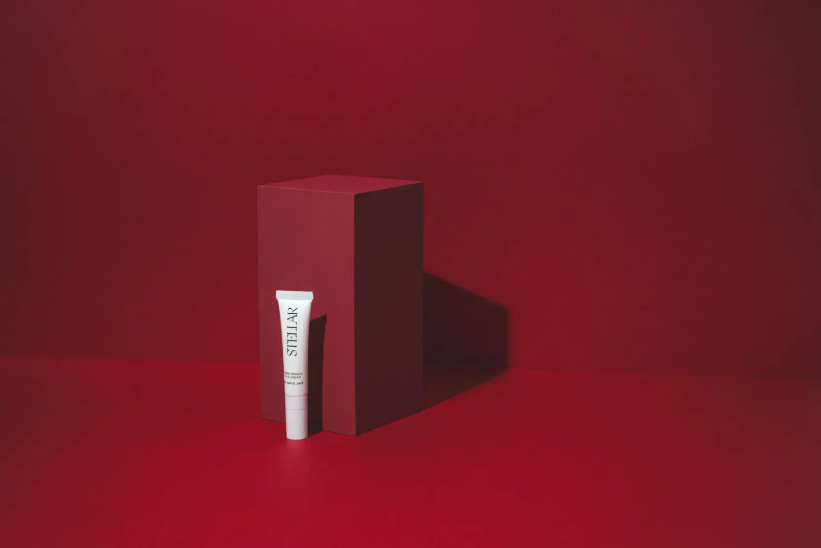 Dr David Jack Meso Renew Eye Cream tube on red pedestal against red background