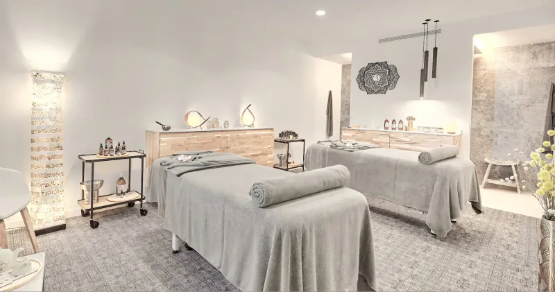 Elegant spa room at Baobab Suites with two massage tables, wooden carts, lamps, and modern decor.