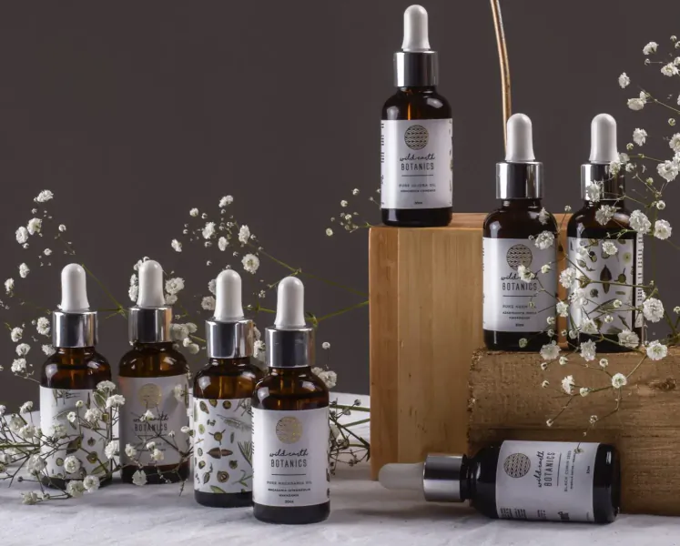 Assortment of Wild Earth Botanics essential oil dropper bottles on wooden stand with baby's breath sprigs