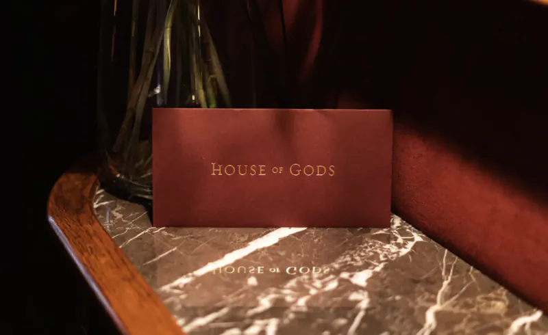 Red 'HOUSE OF GODS' card on marble table beside vase at House of Gods Hotel, Edinburgh