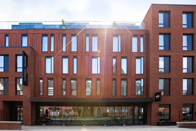 Hotel Indigo Chester, modern red-brick boutique hotel facade with large windows and sunny entrance.