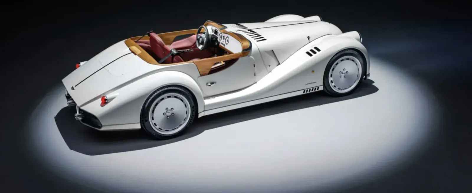 White Morgan Midsummer roadster by Pininfarina, side view with tan leather seats, spotlighted on white background