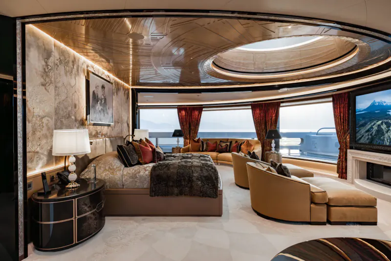 Luxurious yacht master bedroom with king bed, curved sofas, ocean and mountain view.