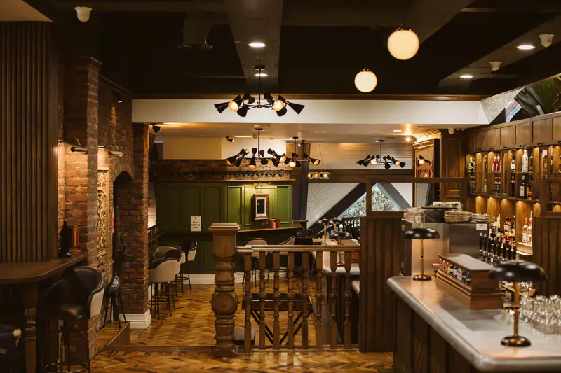 Cozy rustic bar interior at The Rabbit Hotel with wooden counters, brick walls, pendant lights, and bar stools.