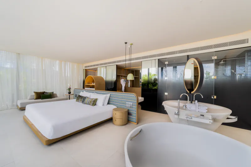 Luxurious SO/ Maldives hotel suite with king bed, freestanding tub, and tropical decor