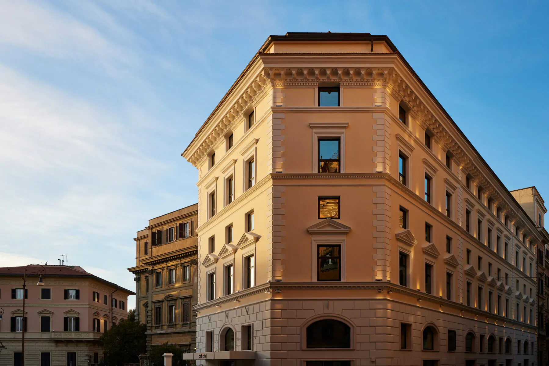 Corner view of art'otel Rome Piazza Sallustio, ornate beige facade glowing in golden sunset light.