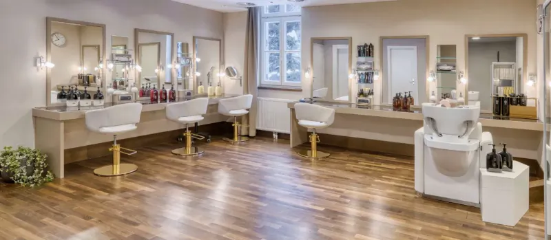 Elegant hair salon at Grand Hotel Des Bains Kempinski St. Moritz with styling stations, mirrors, and wash basins.