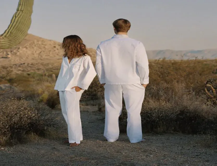 Back view of couple in white pajamas standing in desert with saguaro cactus, for sensitive skin fabrics.