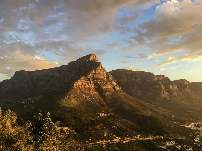 Aerial view of Table Mountain from Cape Town cableway at sunset, with clouds, city below.