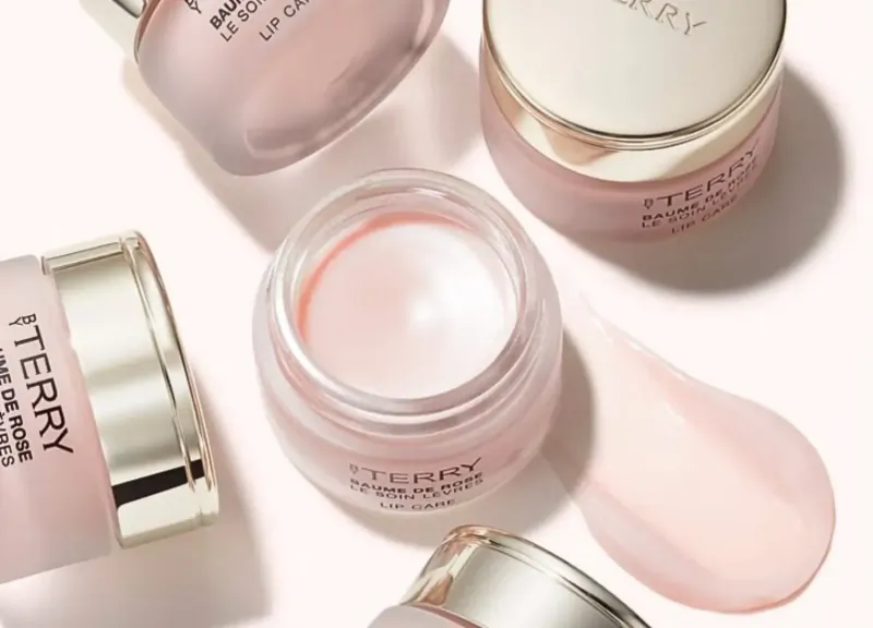 Terry de Gunzburg Baume Lip Cure pink lip balm jars open with pink cream scoop, luxury skincare.