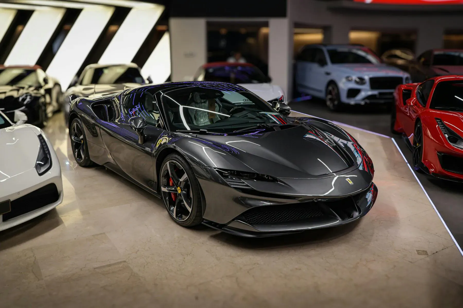 Gray Ferrari SF90 displayed prominently in luxury car showroom among white, red supercars.